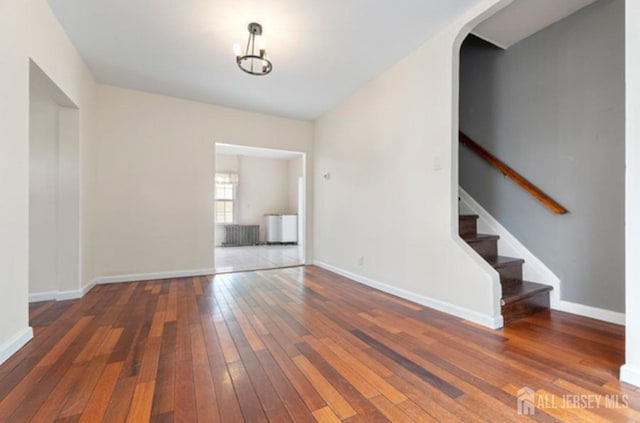 5 Warren St, Jamesburg, NJ 08831 - spare room featuring wood-type flooring, stairs, arched walkways, and a chandelier