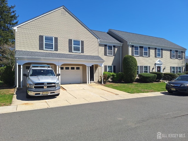 view of front of home with concrete driveway, a shingled roof, and a garage