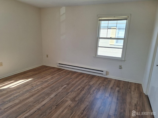 spare room with baseboards, dark wood-style flooring, and baseboard heating