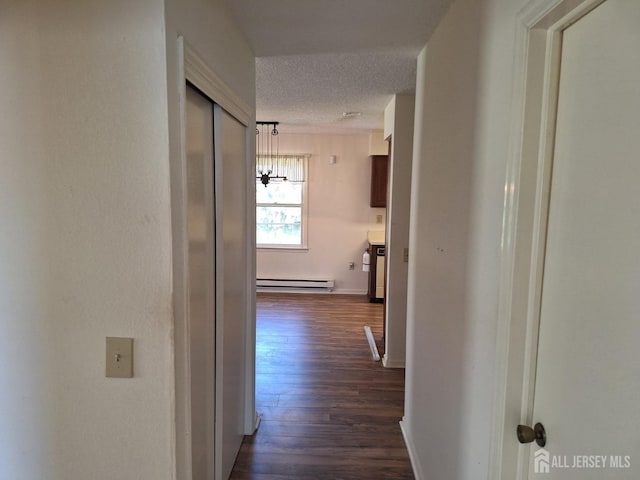 hall featuring a textured ceiling, a baseboard heating unit, baseboards, an inviting chandelier, and dark wood-type flooring