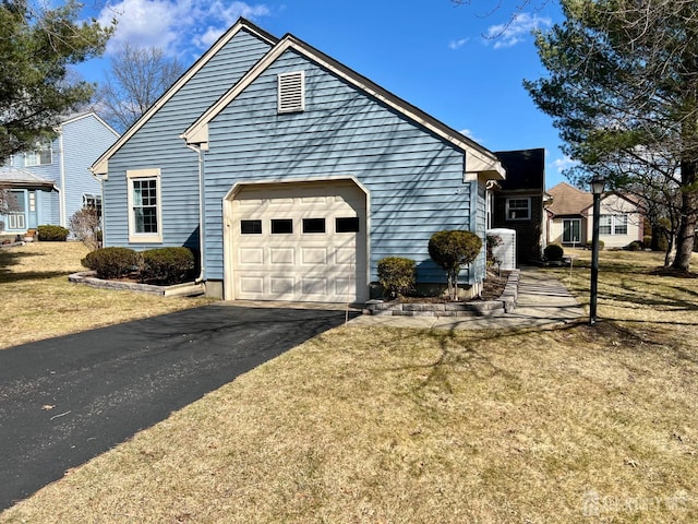 view of side of property with an attached garage, a yard, and driveway