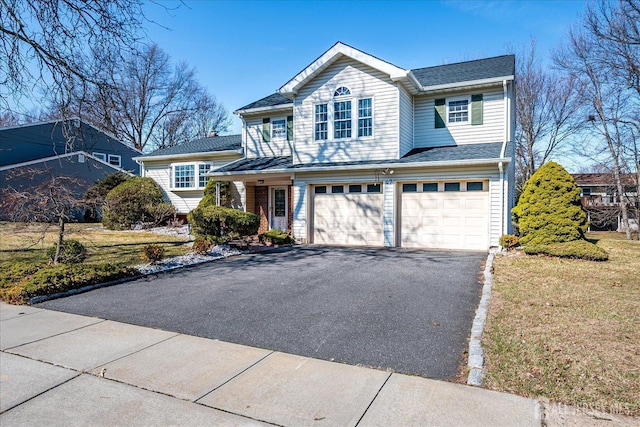 traditional-style house featuring a front lawn, an attached garage, brick siding, and driveway