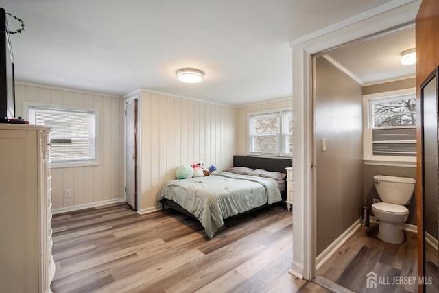 bedroom with light wood-type flooring, baseboards, and ornamental molding