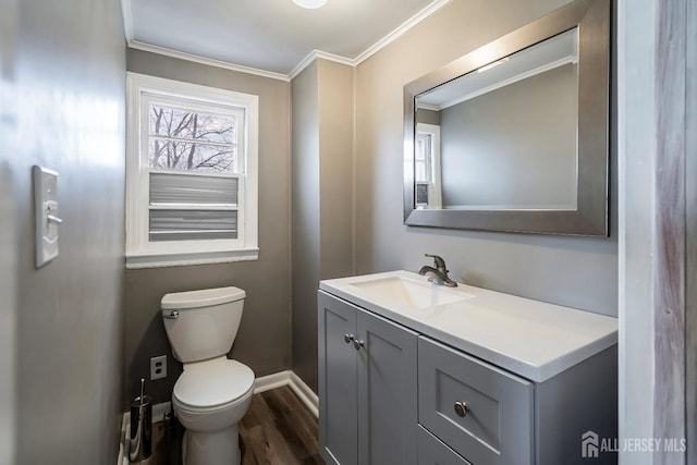 bathroom with baseboards, toilet, ornamental molding, wood finished floors, and vanity