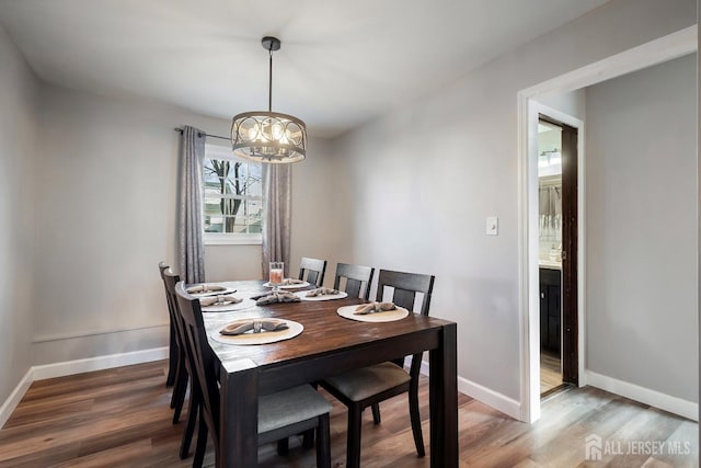 dining area featuring wood finished floors, baseboards, and a chandelier