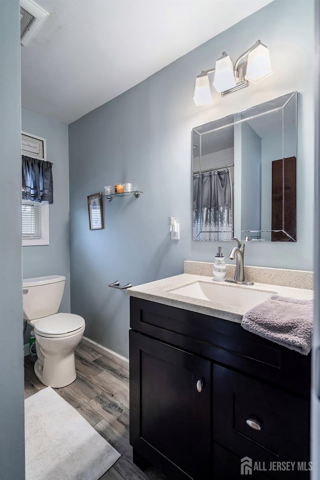 full bath featuring vanity, wood finished floors, visible vents, baseboards, and toilet