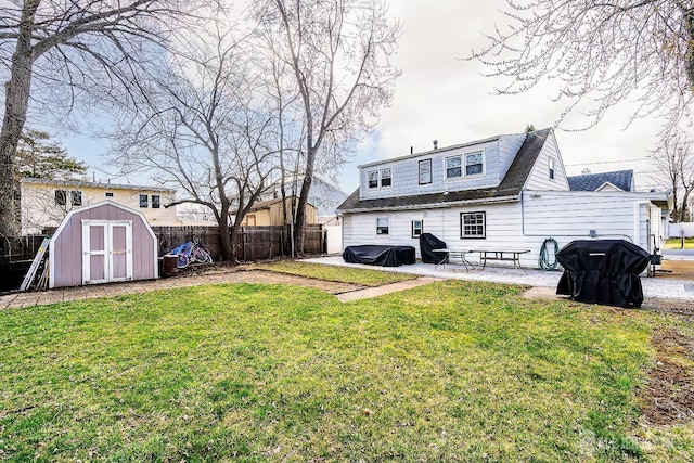 back of property featuring a storage shed, a fenced backyard, a yard, a patio area, and an outbuilding