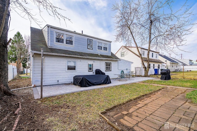 rear view of property featuring a yard, a patio, roof with shingles, and a fenced backyard