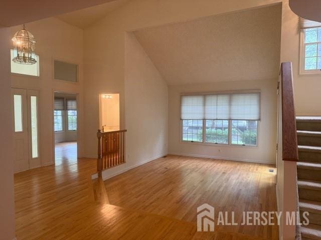 1 Cranberry Ct, South Brunswick, NJ 08540 - unfurnished living room with stairway, a chandelier, wood finished floors, and high vaulted ceiling