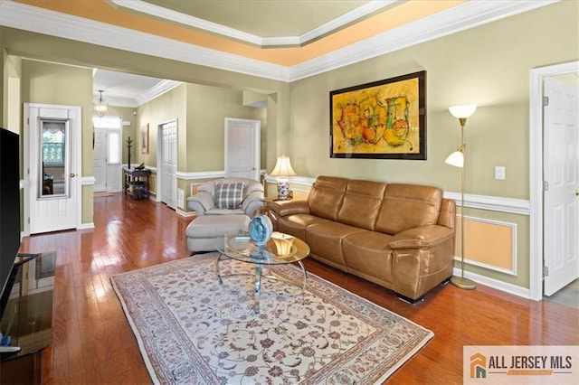 living room featuring ornamental molding, baseboards, hardwood / wood-style floors, and an inviting chandelier