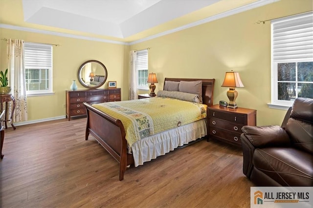 bedroom with ornamental molding, a tray ceiling, wood finished floors, and baseboards