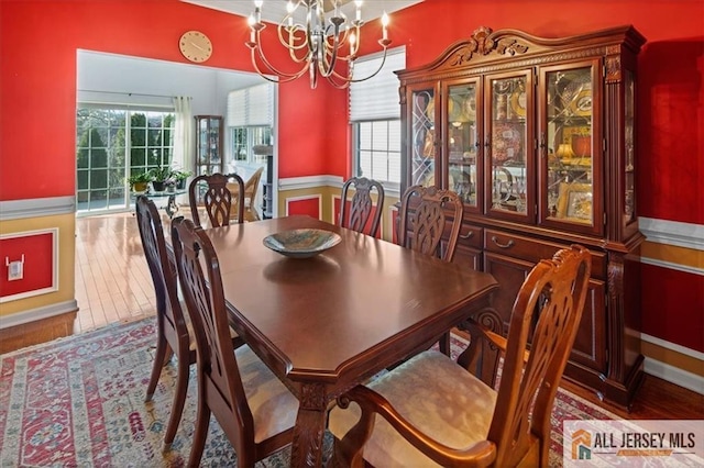 dining room with a healthy amount of sunlight, a chandelier, and wood finished floors