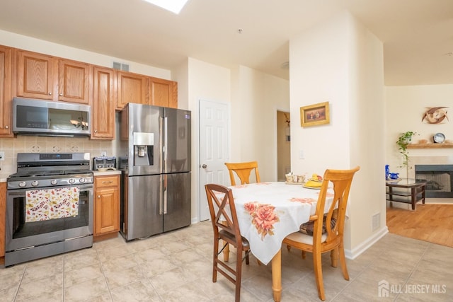 kitchen featuring decorative backsplash, appliances with stainless steel finishes, and light hardwood / wood-style flooring