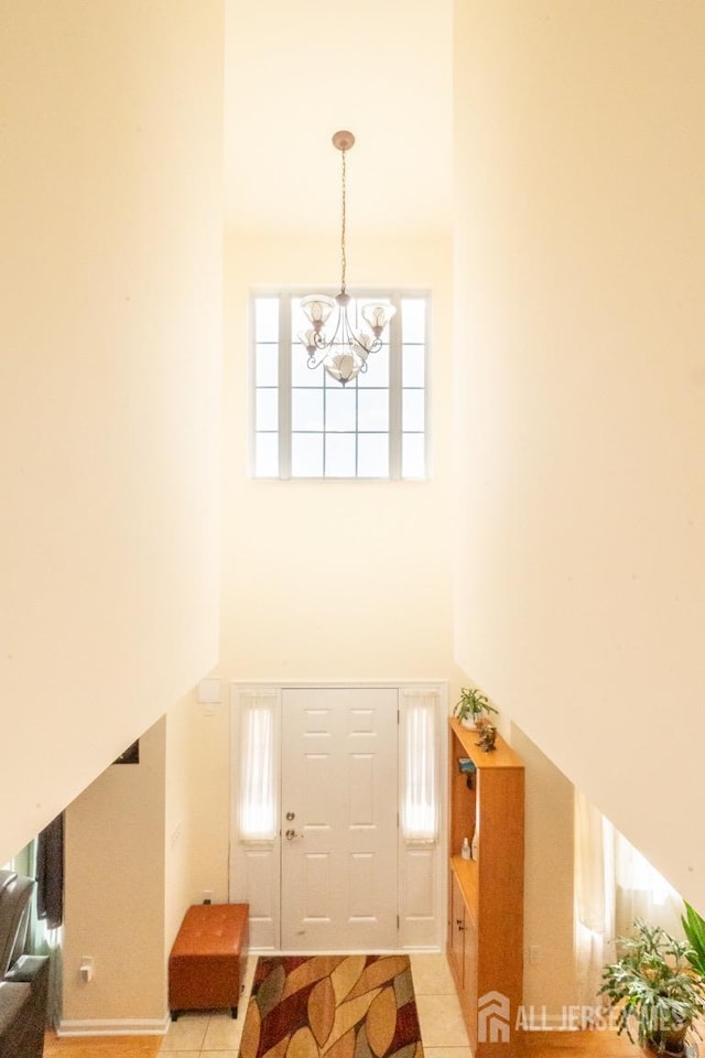 tiled foyer entrance featuring a high ceiling and an inviting chandelier