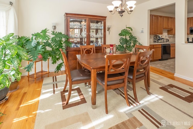 dining space with a wealth of natural light, a notable chandelier, and light hardwood / wood-style flooring