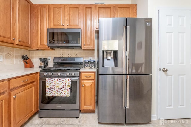 kitchen with backsplash, light tile patterned flooring, and stainless steel appliances