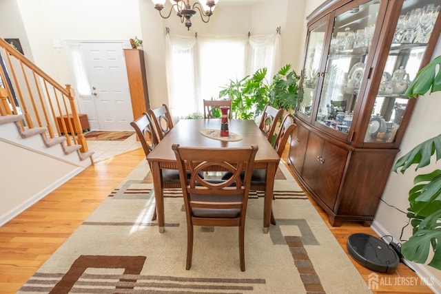 dining space with hardwood / wood-style floors and a notable chandelier