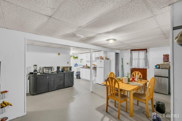 dining space with concrete flooring and a drop ceiling