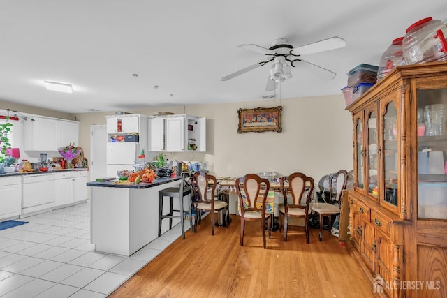 kitchen with white cabinetry, light wood-type flooring, ceiling fan, kitchen peninsula, and white appliances