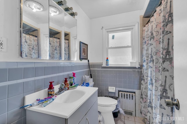 bathroom featuring radiator heating unit, tile walls, vanity, toilet, and tile patterned floors