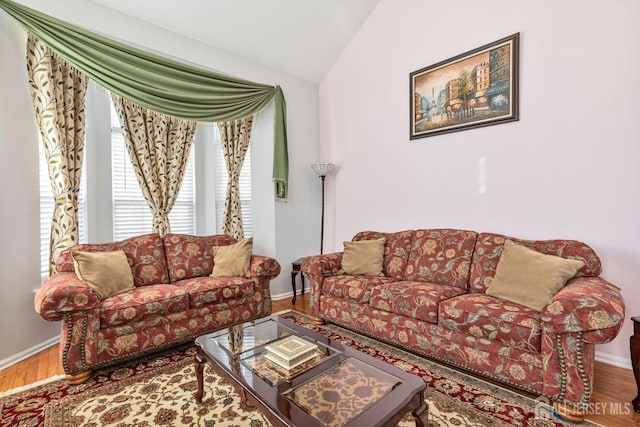 living room with vaulted ceiling, wood finished floors, and baseboards