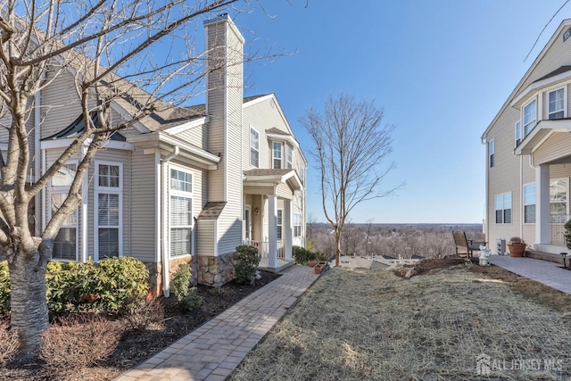 view of side of property with stone siding and a chimney