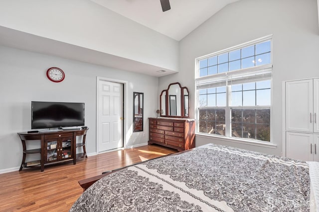 bedroom featuring baseboards, high vaulted ceiling, and light wood-style flooring