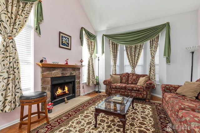 living room with baseboards, wood finished floors, a fireplace, and vaulted ceiling