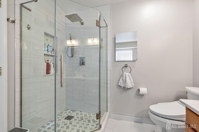 bathroom featuring baseboards, toilet, a shower stall, and vanity