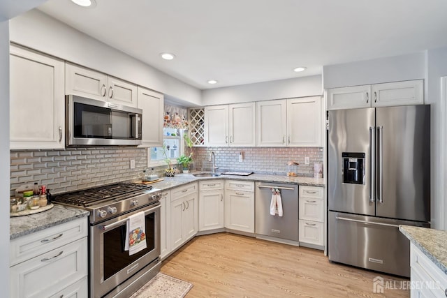 217 Fred Allen Dr, South Plainfield, NJ 07080 - kitchen with appliances with stainless steel finishes, light stone countertops, tasteful backsplash, light wood-style flooring, and white cabinets