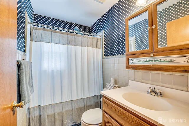 bathroom featuring tile walls, vanity, toilet, wallpapered walls, and a shower with shower curtain