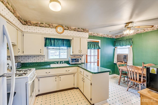kitchen featuring a peninsula, gas range gas stove, plenty of natural light, cream cabinetry, and a sink