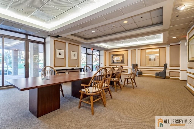 carpeted office with a tray ceiling and a decorative wall