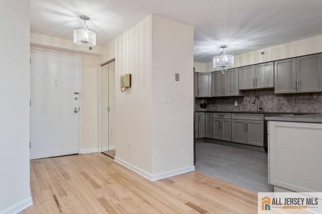 entryway featuring baseboards, light wood-type flooring, and a chandelier
