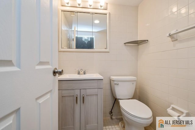 bathroom featuring vanity, toilet, and tile walls