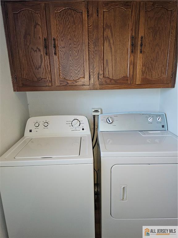 laundry area with independent washer and dryer and cabinets