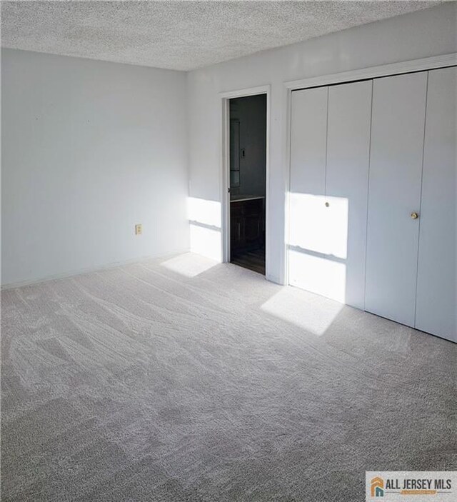 unfurnished bedroom featuring a textured ceiling, carpet, and ensuite bath