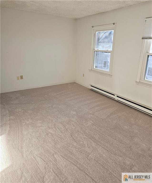 empty room with a baseboard heating unit, a textured ceiling, and light carpet