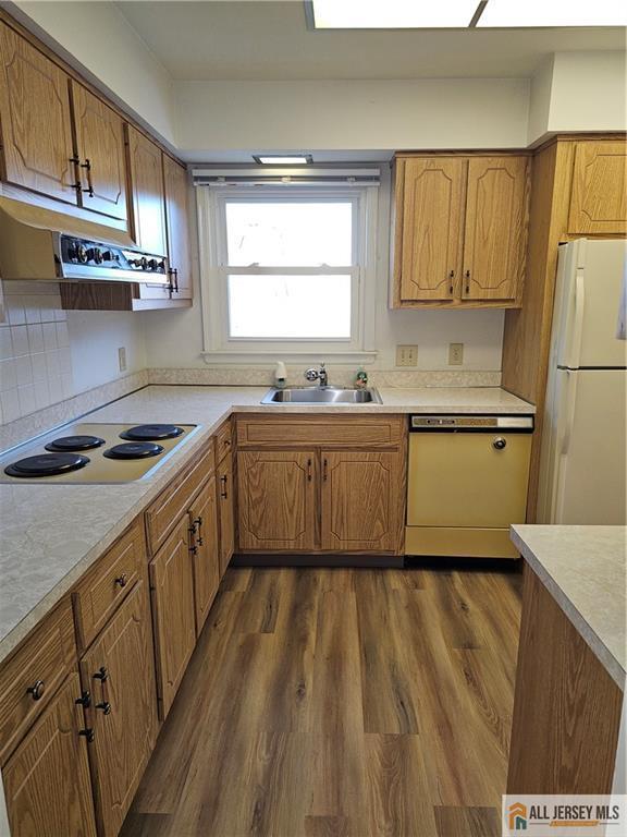 kitchen featuring backsplash, dark wood-type flooring, sink, and white appliances