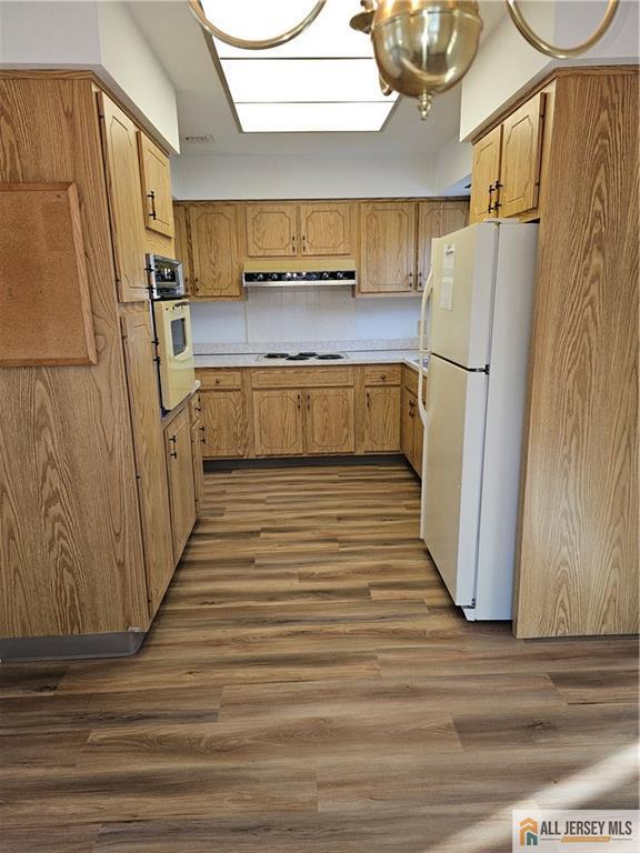 kitchen with white appliances, dark hardwood / wood-style flooring, extractor fan, and tasteful backsplash