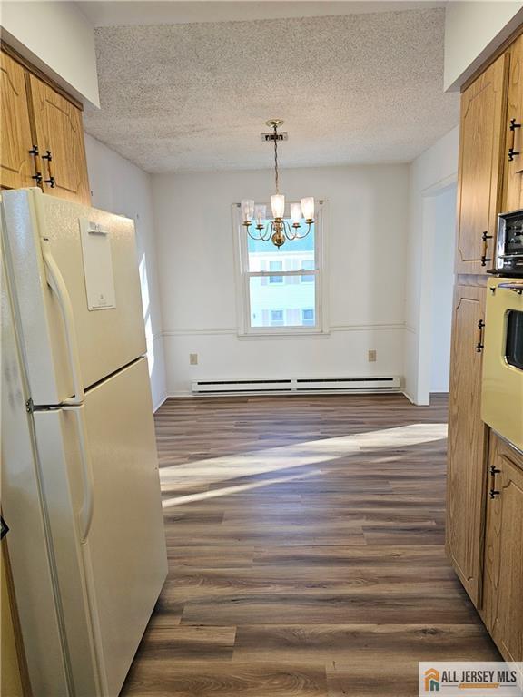 kitchen featuring decorative light fixtures, an inviting chandelier, a textured ceiling, white refrigerator, and a baseboard radiator