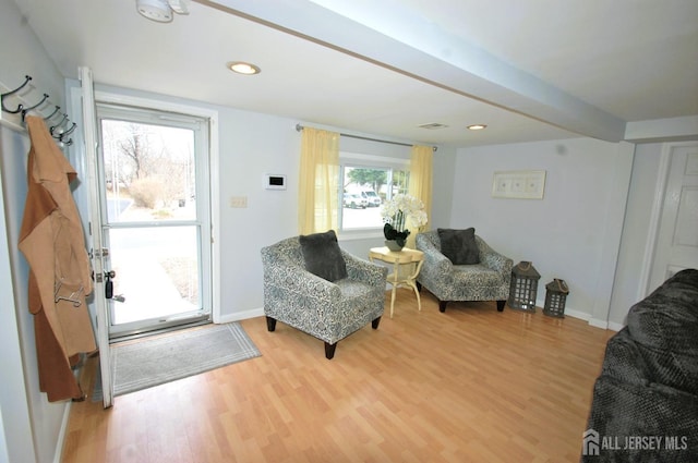 living area featuring light wood finished floors, baseboards, and visible vents