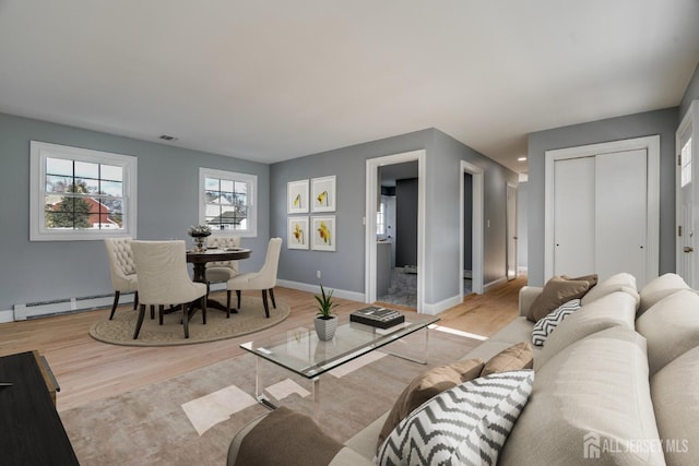 living area featuring wood finished floors, baseboard heating, and baseboards