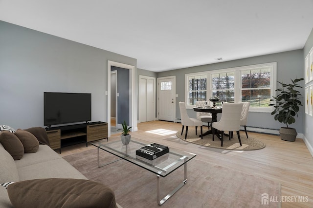 living area featuring wood finished floors, a baseboard heating unit, and baseboards
