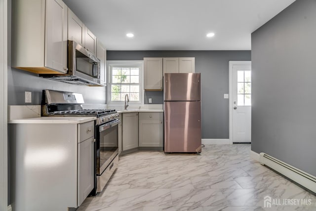 kitchen with stainless steel appliances, baseboards, gray cabinets, light countertops, and a baseboard radiator