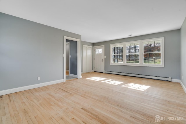 unfurnished living room with baseboards, wood finished floors, and a baseboard radiator