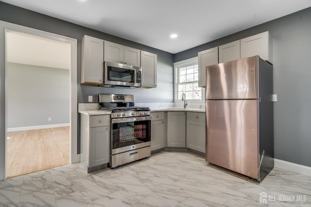 kitchen featuring gray cabinets, marble finish floor, stainless steel appliances, light countertops, and baseboards