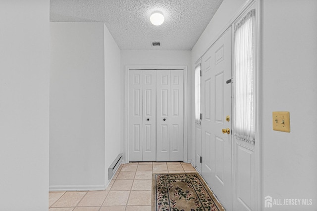 714 Victoria Ct Unit B, Monroe, NJ 08831 - corridor featuring a textured ceiling, light tile patterned flooring, baseboards, and a baseboard radiator