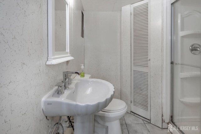 bathroom featuring tile patterned flooring, sink, a shower, and toilet