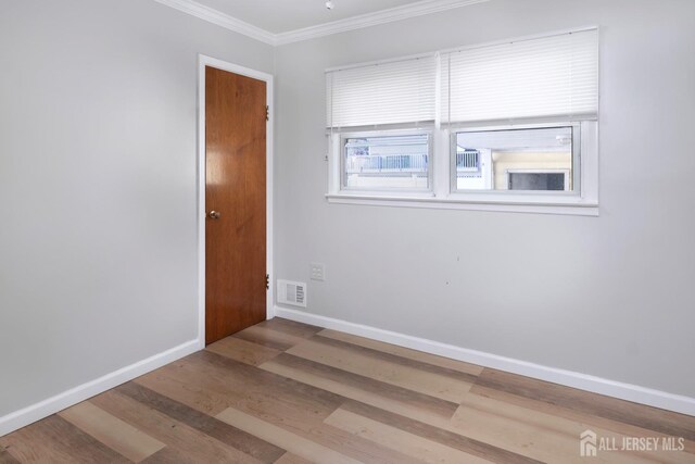 empty room with wood-type flooring and crown molding